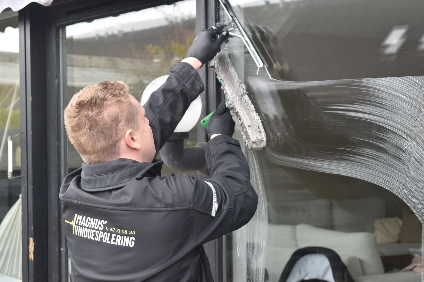 Professional cleaner washing a large window