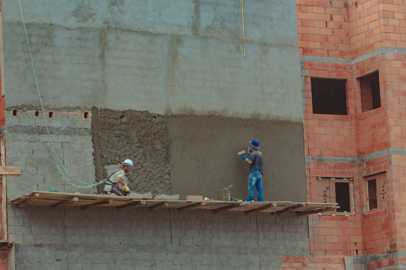 Builders working on a brick wall at a construction site